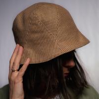 Juliette is wearing a Le Panache Paris© bucket hat made in France with tobacco and ivory stripeweave100% cotton.